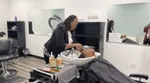 A black woman washes a black woman’s hair, using SheaMoisture products, at a salon in the Polycultural Centre of Excellence